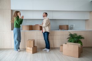 Overjoyed woman jumping, clapping hands of happiness and glad husband relocating into own new flat