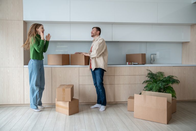 Overjoyed woman jumping, clapping hands of happiness and glad husband relocating into own new flat